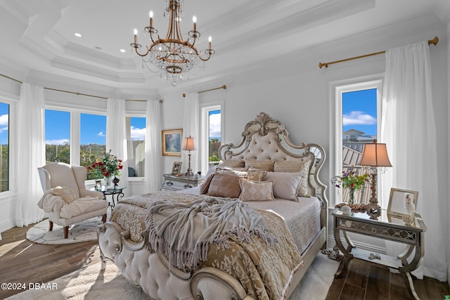 bedroom with a chandelier, wood-type flooring, ornamental molding, and a raised ceiling