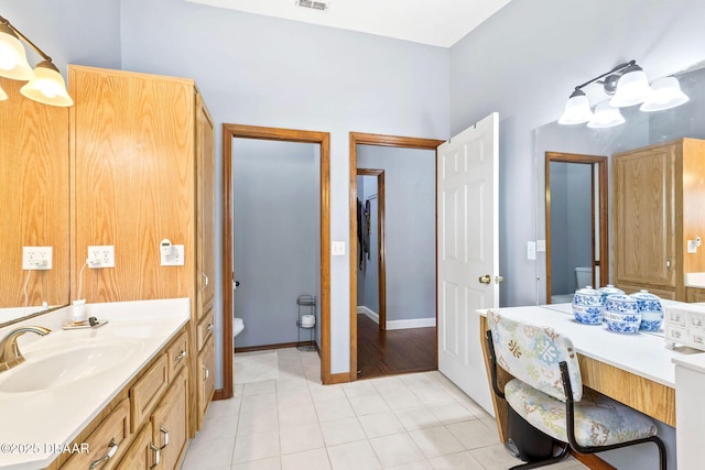 full bath with toilet, visible vents, vanity, baseboards, and tile patterned floors