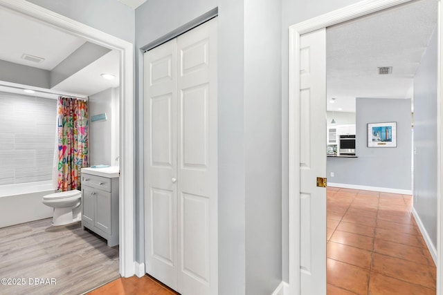 full bath featuring shower / bath combo, baseboards, visible vents, toilet, and vanity