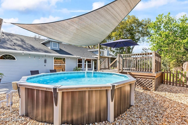 outdoor pool featuring fence and a deck