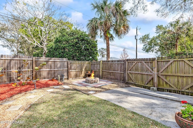 view of yard featuring a fenced backyard, a gate, a fire pit, and a patio