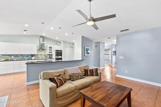 living room with ceiling fan, light tile patterned flooring, visible vents, baseboards, and vaulted ceiling