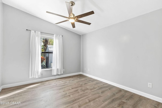 spare room with lofted ceiling, baseboards, and wood finished floors