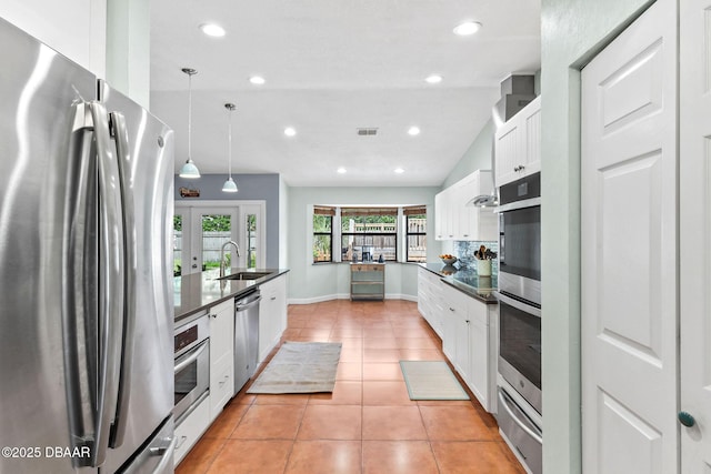 kitchen with a sink, visible vents, appliances with stainless steel finishes, a warming drawer, and dark countertops