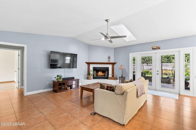 living area with lofted ceiling, a brick fireplace, ceiling fan, and light tile patterned floors