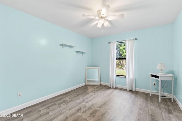 spare room featuring a ceiling fan, baseboards, and wood finished floors