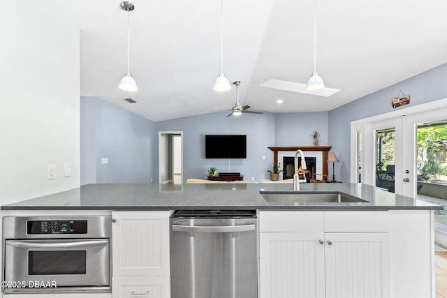 kitchen featuring stainless steel appliances, dark stone countertops, a sink, and white cabinets