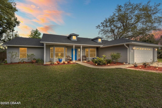 view of front of house with a garage, roof with shingles, and a yard