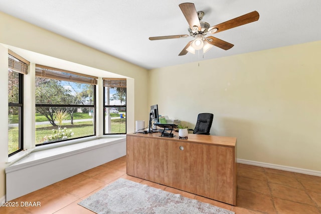 tiled office space featuring a ceiling fan and baseboards