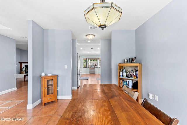 hallway with baseboards, visible vents, and light tile patterned flooring