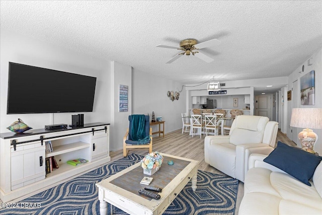 living room with ceiling fan, wood-type flooring, and a textured ceiling