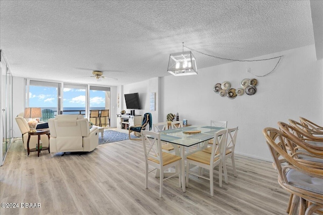 dining room featuring a textured ceiling, floor to ceiling windows, ceiling fan with notable chandelier, and light hardwood / wood-style flooring