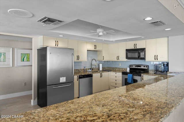 kitchen with stainless steel appliances, stone countertops, sink, kitchen peninsula, and cream cabinetry