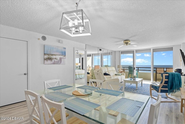 dining space with expansive windows, a textured ceiling, light hardwood / wood-style floors, and ceiling fan with notable chandelier