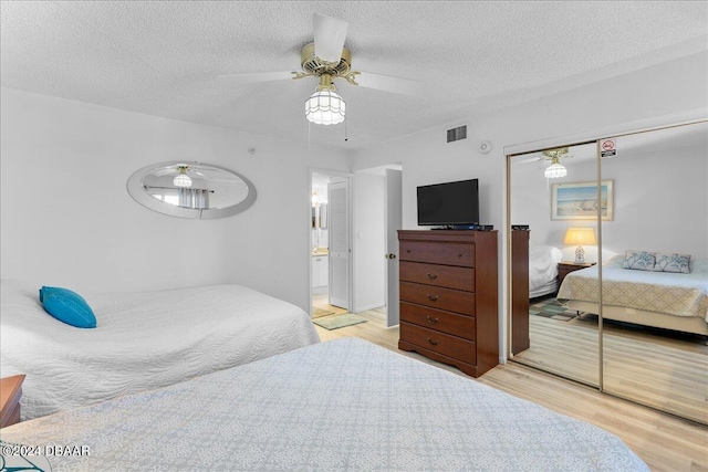 bedroom featuring a closet, light hardwood / wood-style floors, a textured ceiling, and ceiling fan