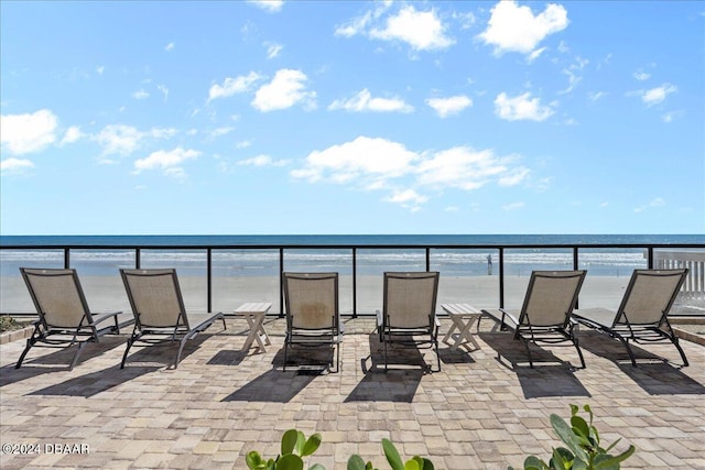 view of patio / terrace featuring a balcony, a view of the beach, and a water view