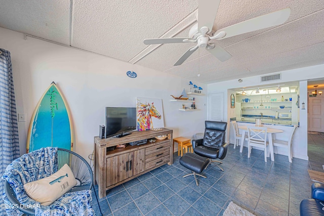 living room featuring ceiling fan and a textured ceiling