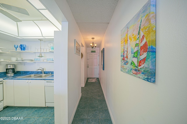 hall with sink, a textured ceiling, and a chandelier