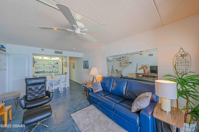 living room featuring ceiling fan and a textured ceiling