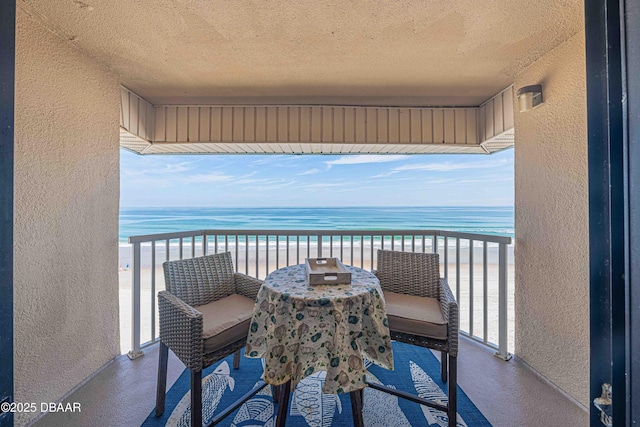 balcony with a water view and a view of the beach