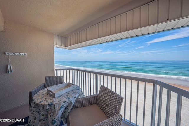 balcony with a water view and a view of the beach