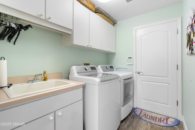 laundry room with sink, cabinets, wood-type flooring, separate washer and dryer, and a textured ceiling