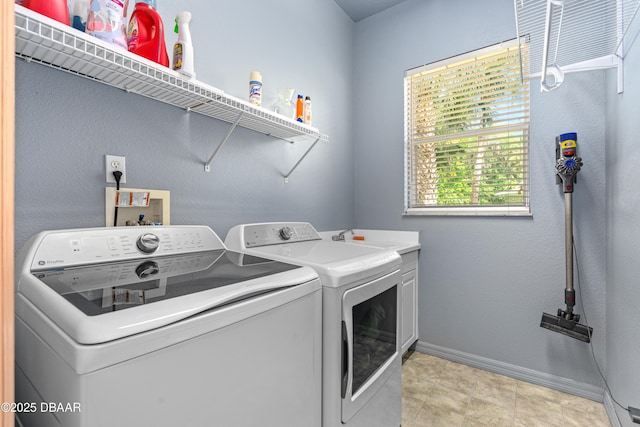 clothes washing area with separate washer and dryer, cabinet space, and baseboards
