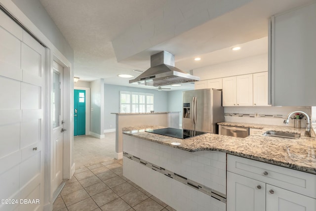 kitchen with light stone countertops, appliances with stainless steel finishes, island range hood, sink, and white cabinets