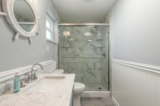 bathroom with an enclosed shower, vanity, toilet, and wood-type flooring