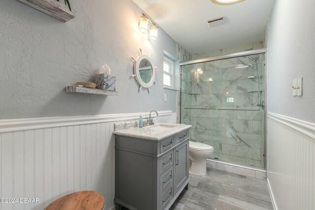 bathroom featuring hardwood / wood-style floors, vanity, toilet, and a shower with door