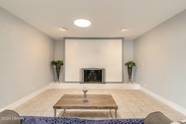 living room with a large fireplace and light tile patterned floors