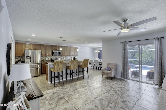61 Levee Ln, Ormond Beach, FL 32174 - kitchen with appliances with stainless steel finishes, tasteful backsplash, ceiling fan, a textured ceiling, and a breakfast bar area
