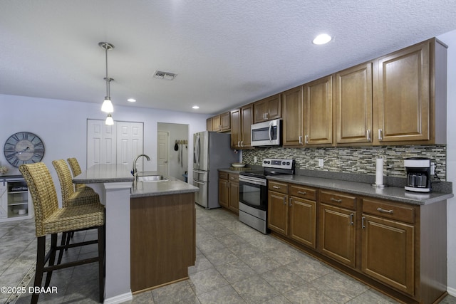61 Levee Ln, Ormond Beach, FL 32174 - kitchen featuring appliances with stainless steel finishes, dark countertops, a kitchen bar, backsplash, and a kitchen island with sink
