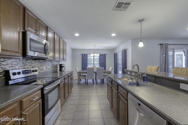 61 Levee Ln, Ormond Beach, FL 32174 - kitchen with appliances with stainless steel finishes, dark countertops, backsplash, a chandelier, and hanging light fixtures