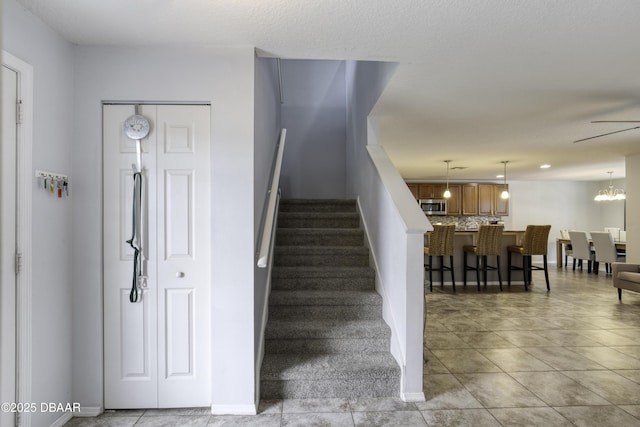 61 Levee Ln, Ormond Beach, FL 32174 - stairs with tile patterned floors and a chandelier