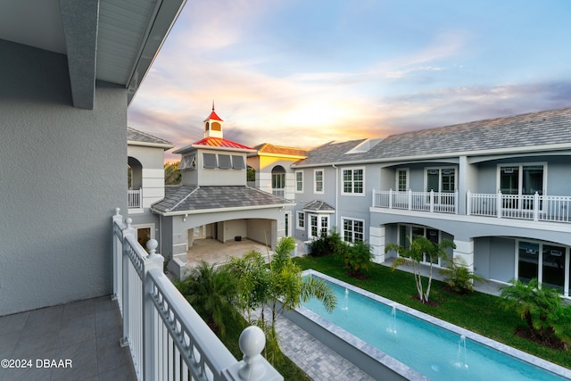 balcony at dusk featuring pool water feature