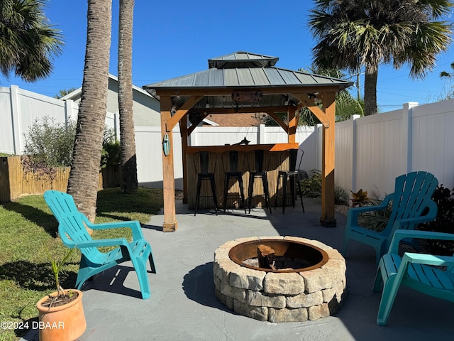 view of patio / terrace featuring a gazebo, a bar, and a fire pit