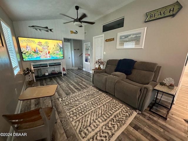 living room featuring ceiling fan, wood walls, wood-type flooring, and vaulted ceiling