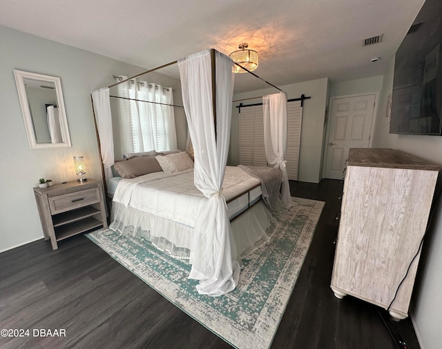 bedroom featuring a barn door and dark wood-type flooring