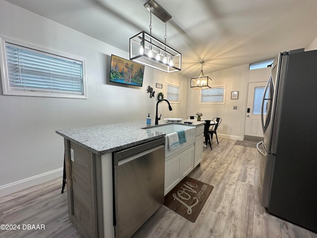 kitchen featuring white cabinetry, sink, hanging light fixtures, stainless steel appliances, and light wood-type flooring