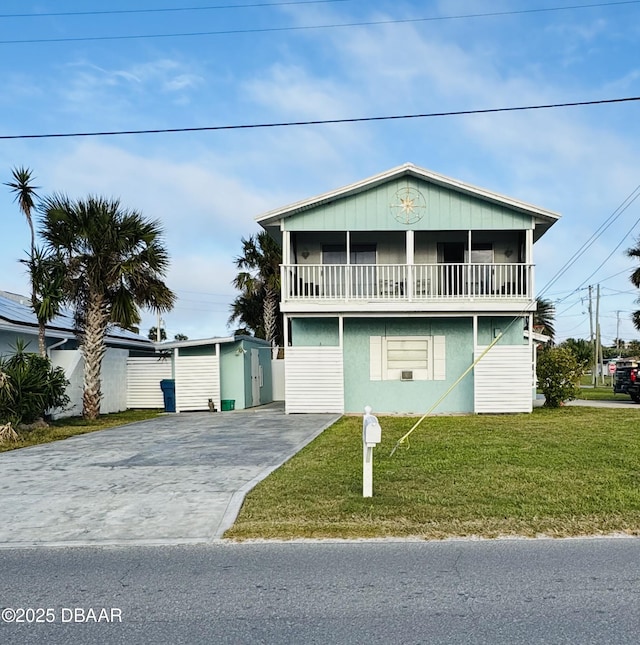 view of front facade featuring a balcony, a front lawn, and a storage shed