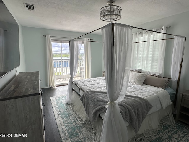 bedroom with dark hardwood / wood-style flooring, access to exterior, and a textured ceiling