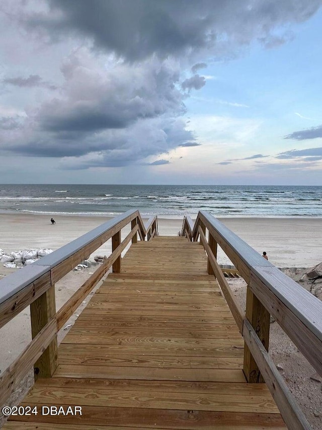 view of dock with a water view and a beach view