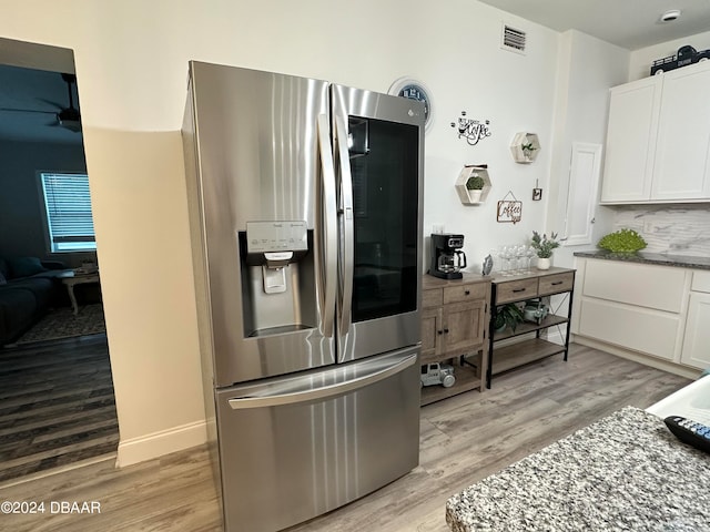 kitchen with light stone countertops, stainless steel fridge with ice dispenser, light hardwood / wood-style flooring, and white cabinetry