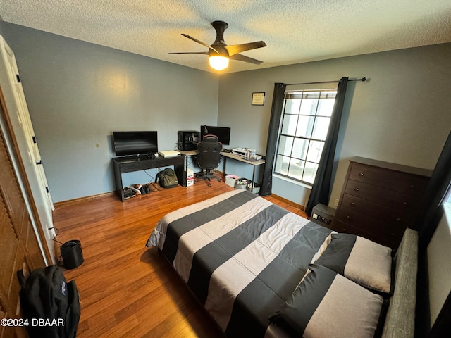 bedroom with a textured ceiling, hardwood / wood-style flooring, and ceiling fan