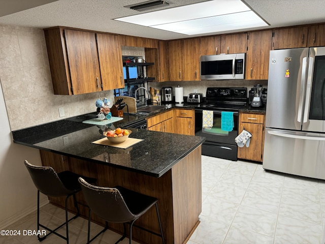 kitchen with black appliances, decorative backsplash, sink, a breakfast bar area, and kitchen peninsula