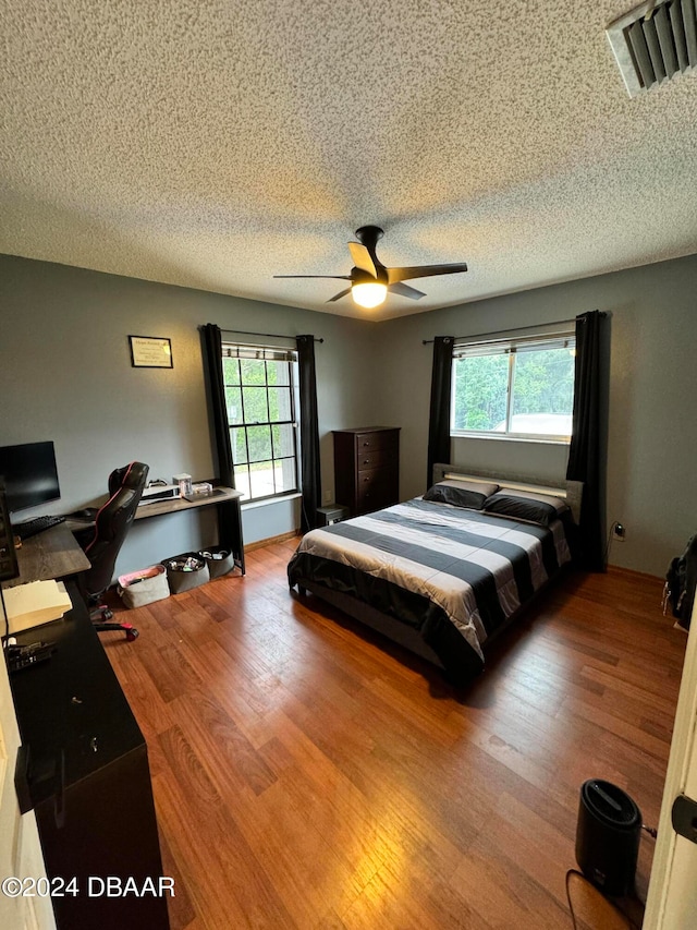 bedroom featuring multiple windows, hardwood / wood-style floors, and ceiling fan