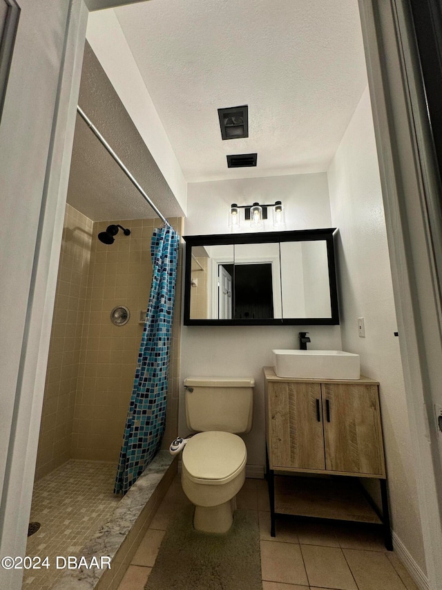 bathroom with tile patterned flooring, a textured ceiling, curtained shower, vanity, and toilet