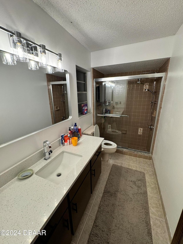 bathroom featuring tile patterned floors, vanity, a textured ceiling, an enclosed shower, and toilet