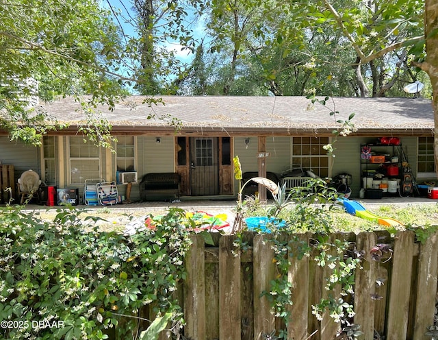 back of house featuring fence and roof with shingles